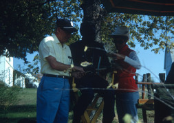 Production crew and Director Gordon Parks (obscured) discussing a document outside of Winger home set.