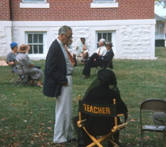 Actress in ‚ÄúTeacher‚Äù chair, likely Hope Summers (Mrs. Kiner), talking to actor and seated with other actors outside of courthouse building used in trial scene.