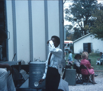 Actor Kyle Johnson (Newt Winger) taking a drink, while other actors sit in the background.