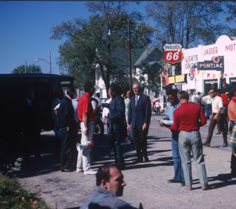 Actors and crew preparing for a scene in downtown Fort Scott, Kansas. Director Gordon Parks (in blue denim) gives instructions, center. Stephen Perry (Jappy), in blue shirt and jeans, consults a book.