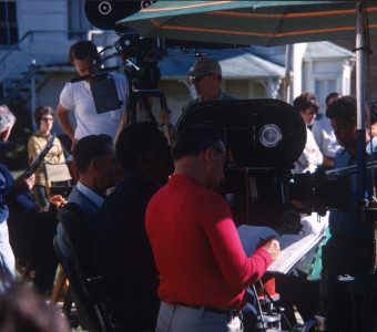 Production crew preparing for filming.Director Gordon Parks is seated in the center behind the camera.