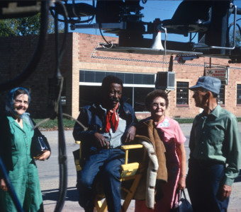 Director Gordon Parks smiles from director‚Äôs chair alongside likely fans in downtown Fort Scott, Kansas.