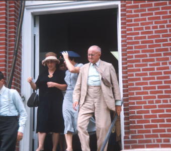 Two actors and two actresses exiting courthouse building, in formal attire, likely around filming of trial scene.