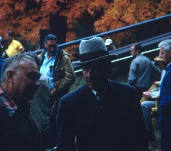 Left to right, actors Russell Thorson (Judge Cavanagh), Mira Waters (Arcella), and Carol Lamond (Big Mabel) sit in front of a production truck.