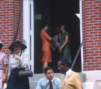 Actors andactresses mill around the entrance of the courthouse building, likely around the filming of the trial scene.