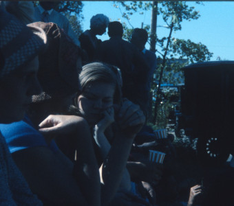 Actors and crew in shadow watching the filming of a scene.