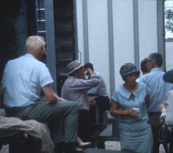 Cast members and production crew taking a break by production trucks.