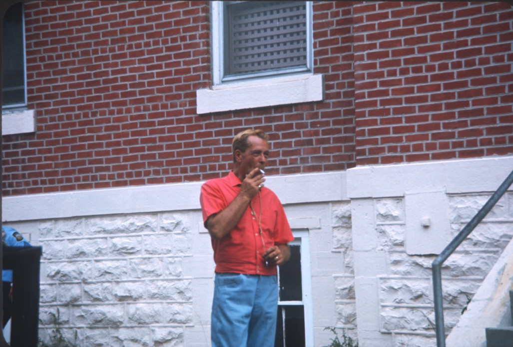 Crew member smoking a cigarette next to the courthouse building.