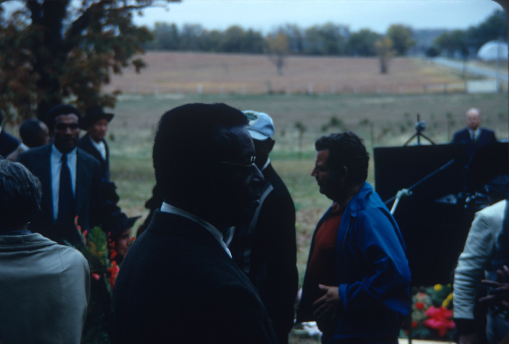 Actor Joel Flullen (Uncle Rob), wearing glasses, and other actors and production crew filming Sarah Winger‚Äôs funeral scene.