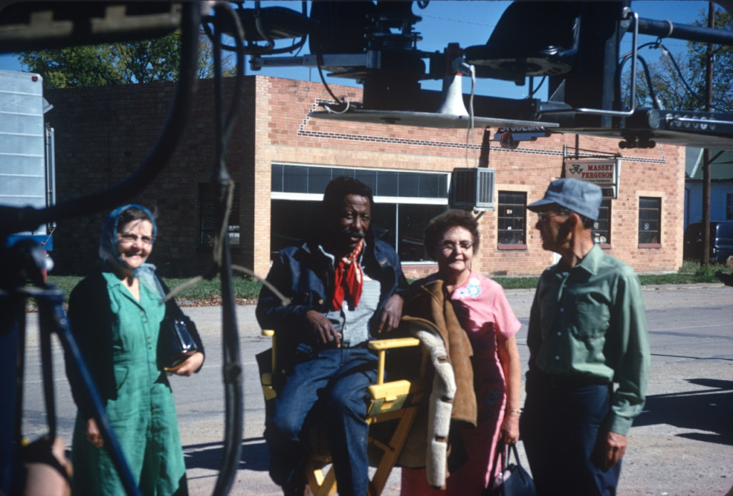 Director Gordon Parks smiles from director‚Äôs chair alongside likely fans in downtown Fort Scott, Kansas.