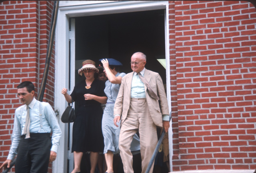 Two actors and two actresses exiting courthouse building, in formal attire, likely around filming of trial scene.