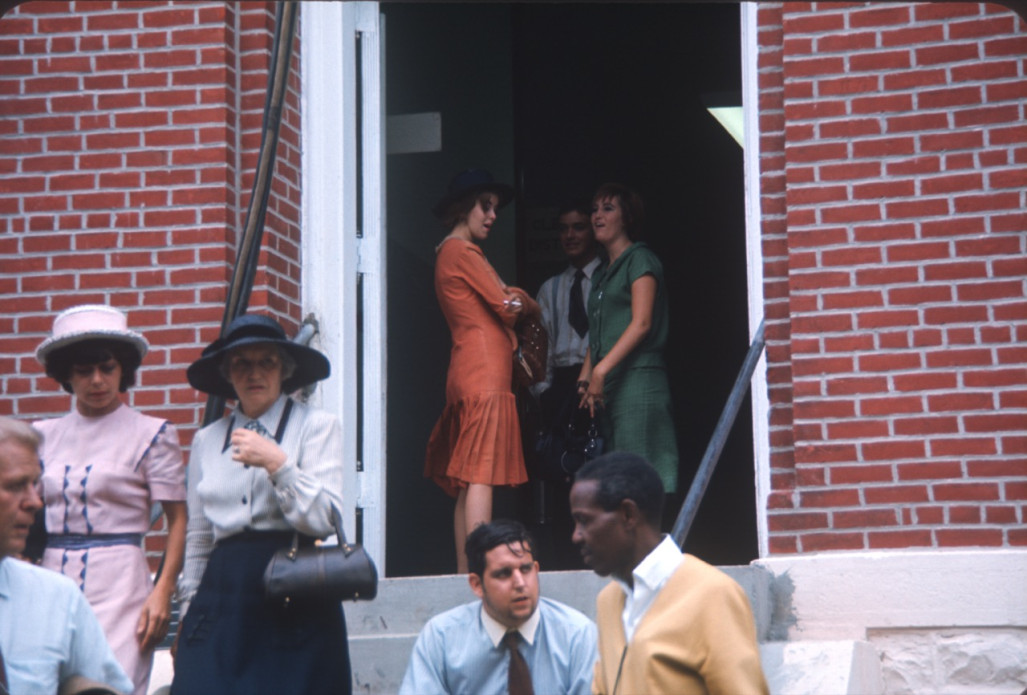 Actors andactresses mill around the entrance of the courthouse building, likely around the filming of the trial scene.