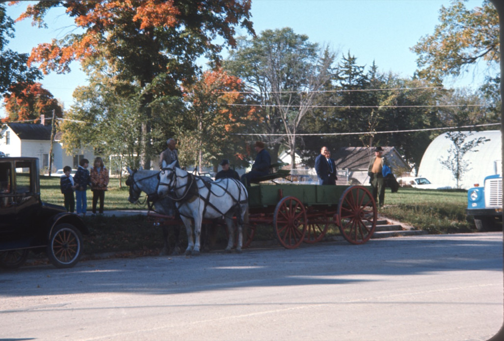 Wagon and horses waiting on the side of a street in downtown Fort Scott with crew members behind it.