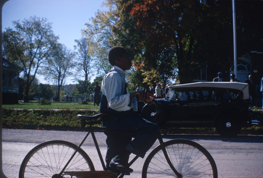 Actor riding a bike in the street by courthouse.