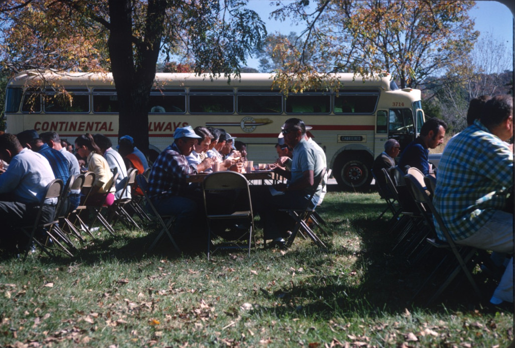 Cast and crew eating a meal in front of production bus.