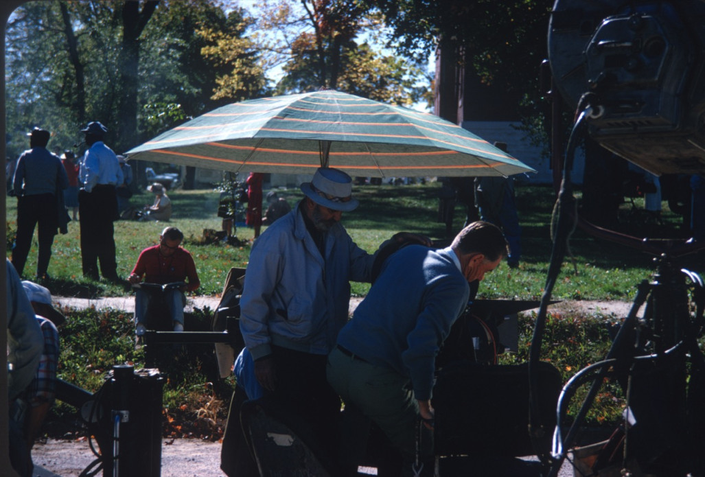 Crew standing underneath an umbrella with production equipment.