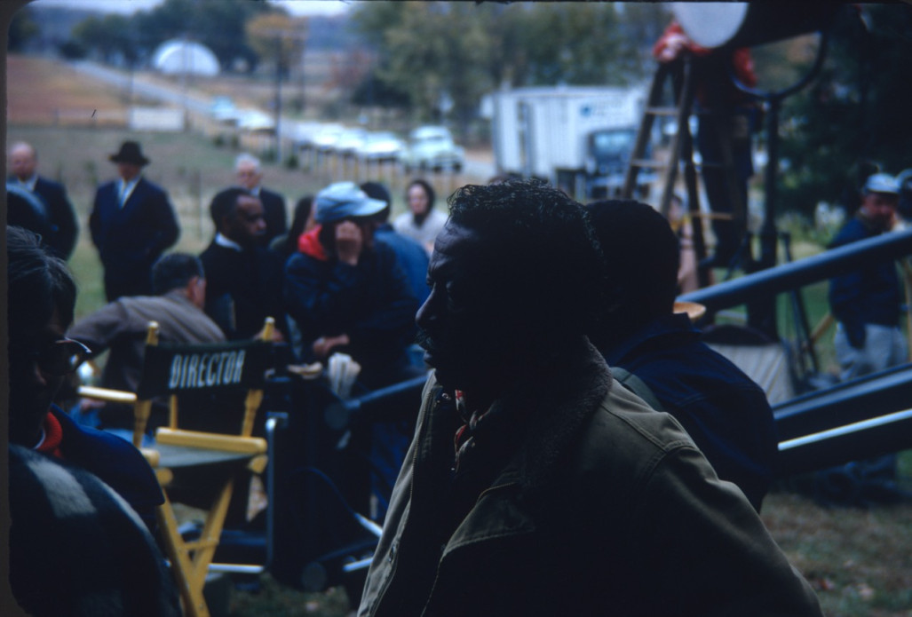 Director Gordon Parks in front with cast and crew members and production equipment behind him.